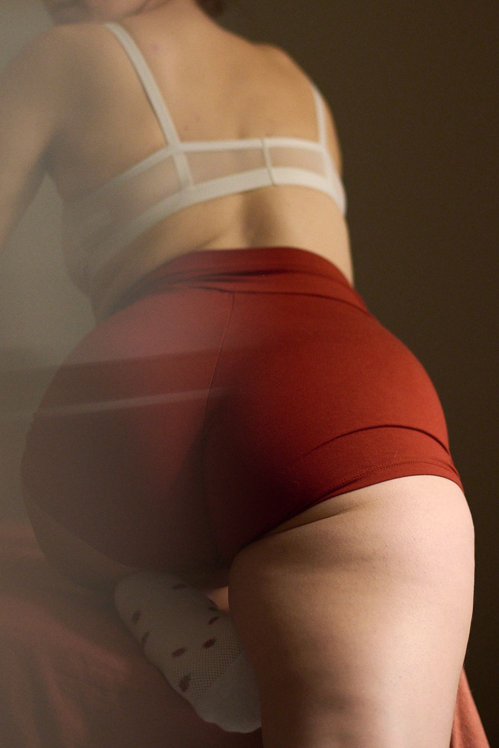 Rear view of woman in white strappy bra and red high-waist shorts.