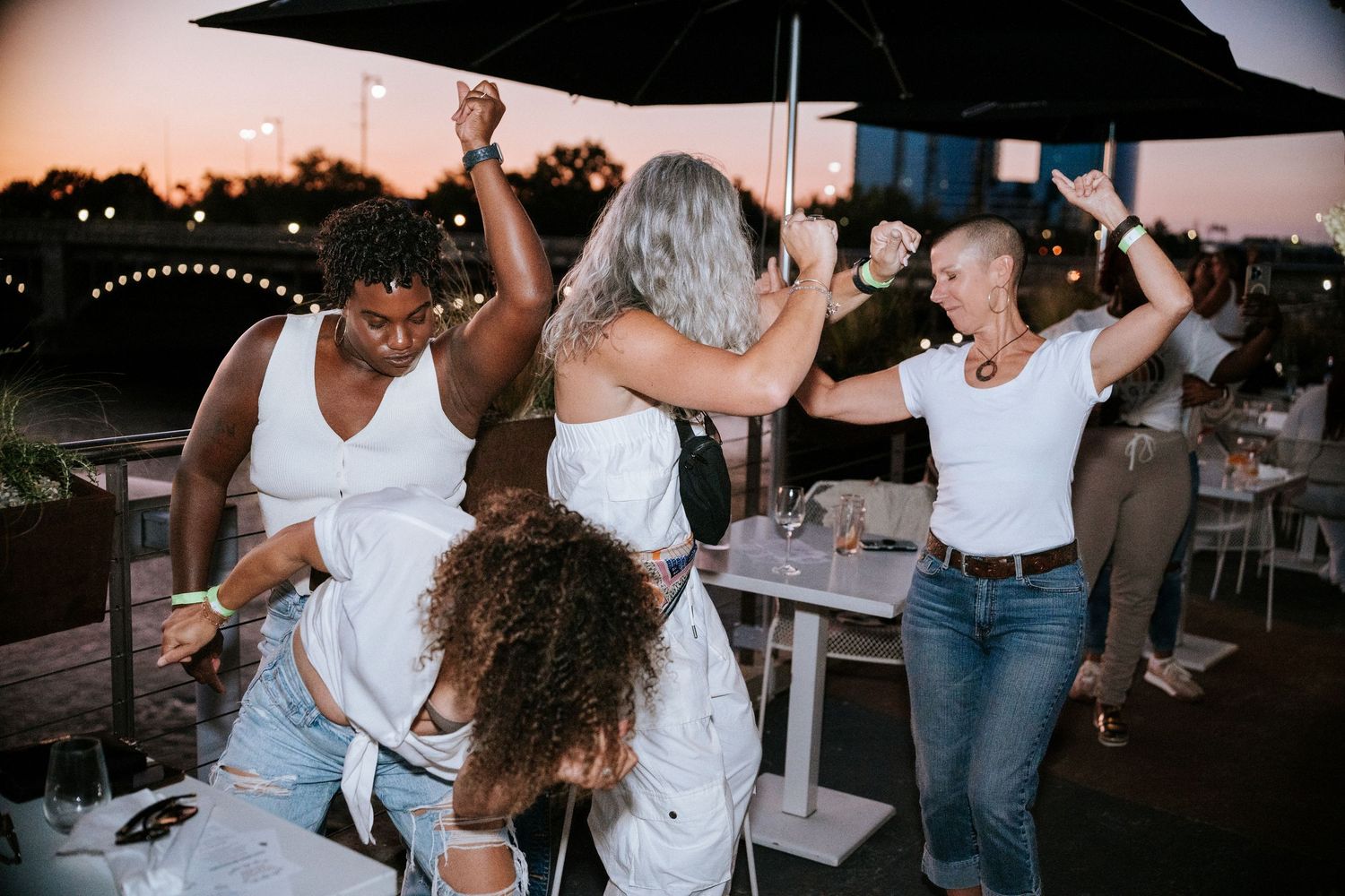 Group of people dancing and celebrating at an outdoor evening party.