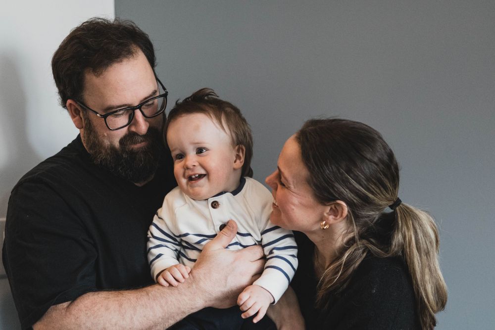 Studio family portraits showing joyful interactions against grey background.
