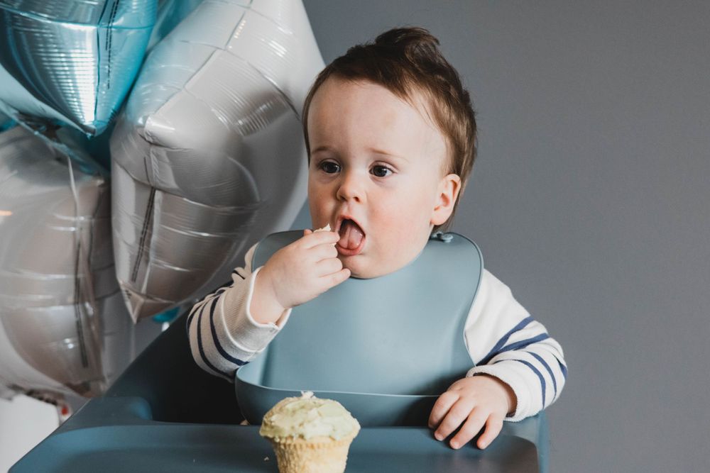 Baby's first birthday celebration with silver balloons and decorations in studio setting.