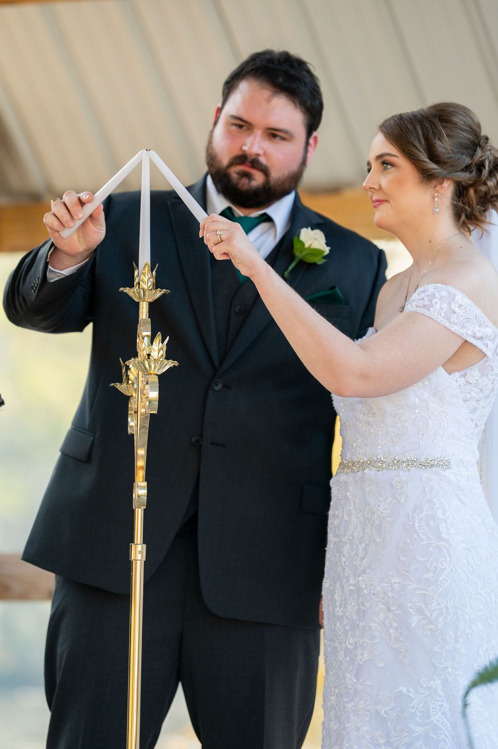 Wedding ceremony moment with couple lighting unity candles at the altar.