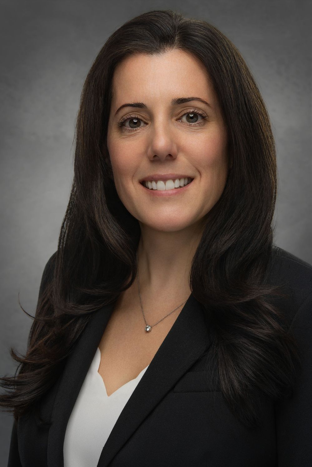 Professional headshot portraits of someone in a black blazer and white top against a gray background.