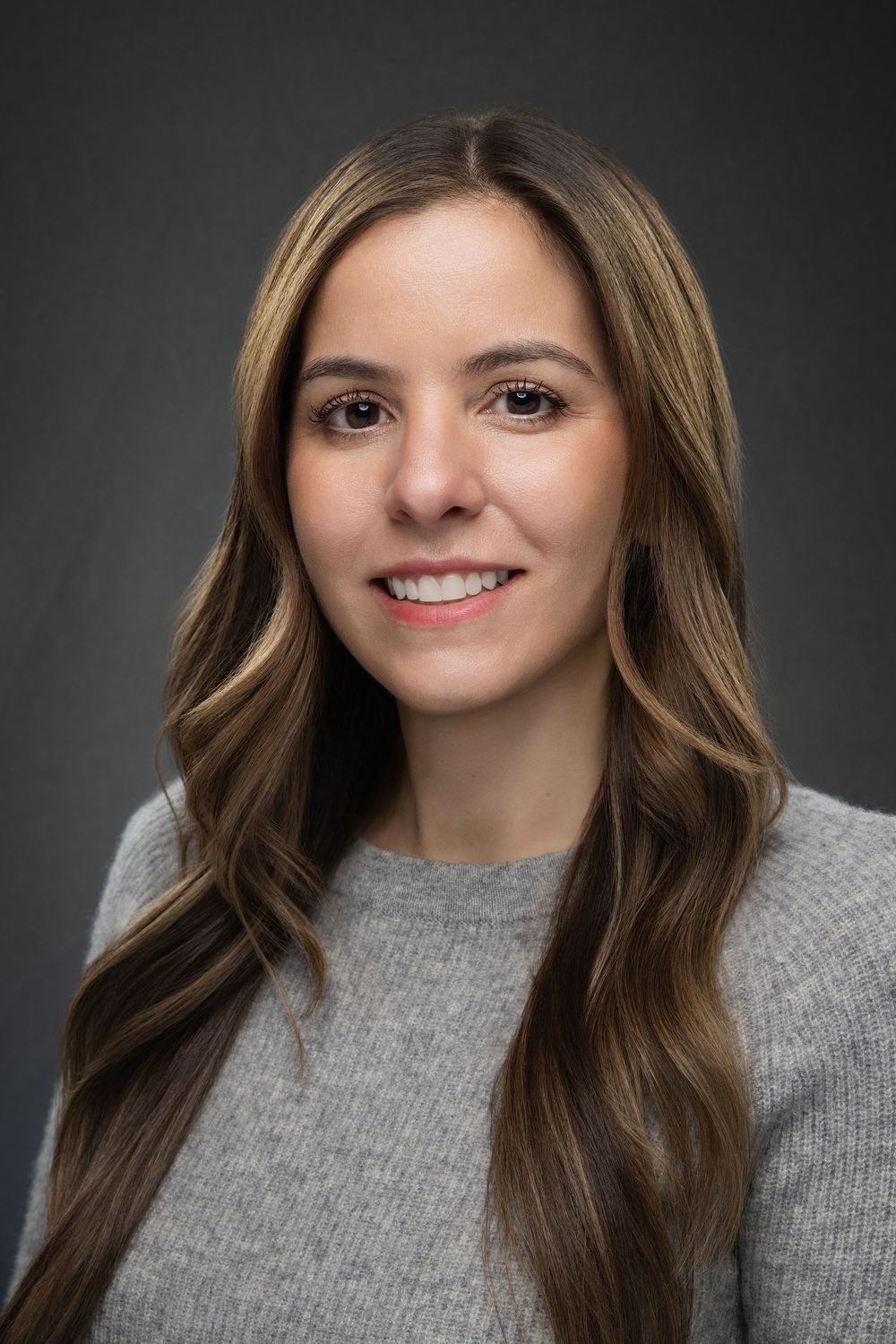 Professional headshot series showing joyful expressions in a grey sweater against dark background.