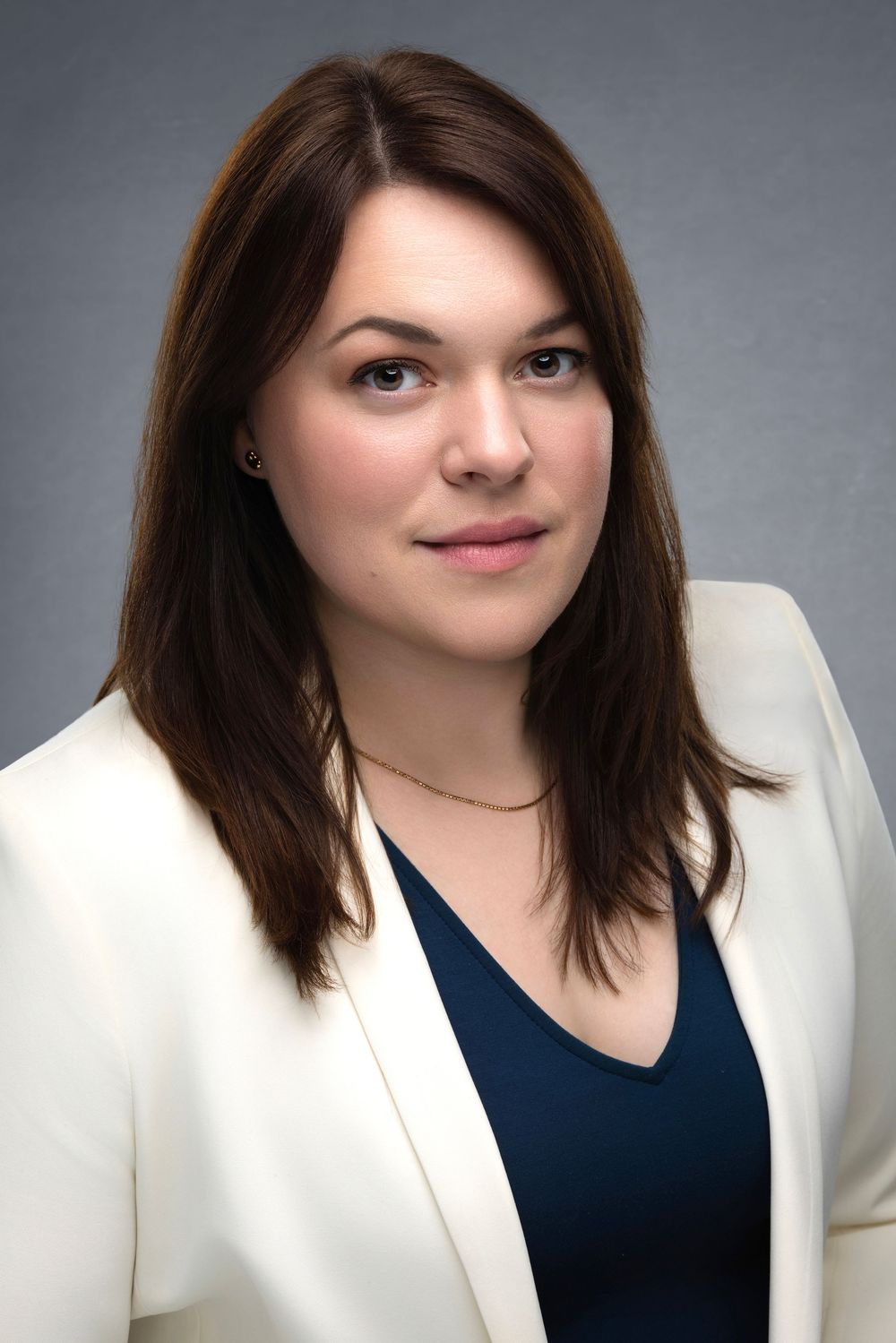 Professional headshot series showing different angles and expressions while wearing a white blazer and navy top.