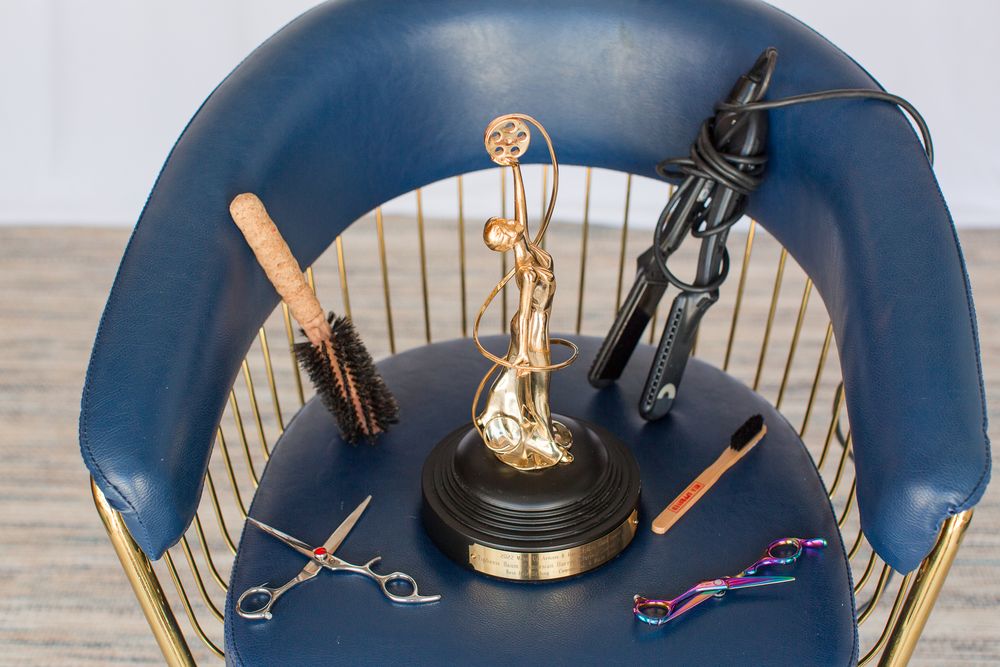 Trophy award displayed on blue chair with hair styling tools arranged around it.