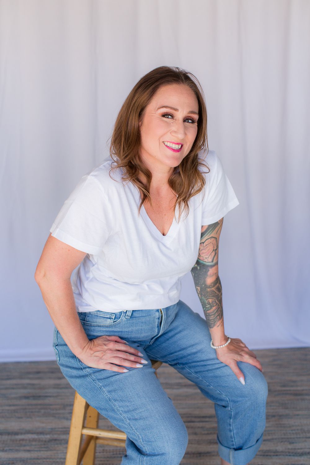 Professional studio photo shoot with white shirt and jeans against light gray backdrop in casual poses.