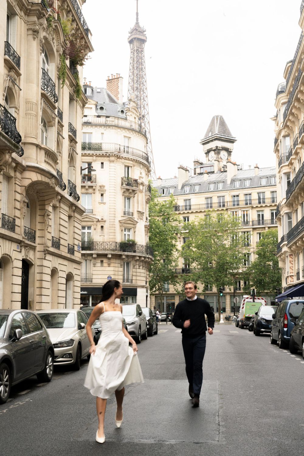 Couple walking down a charming Parisian street with classic Haussmann architecture and the Eiffel Tower. Cinematic photography Paris