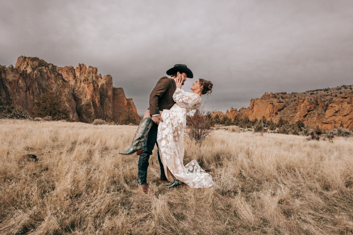 Ellensburg, WA wedding couple kissing in a green field with a cowboy hat in front of them.