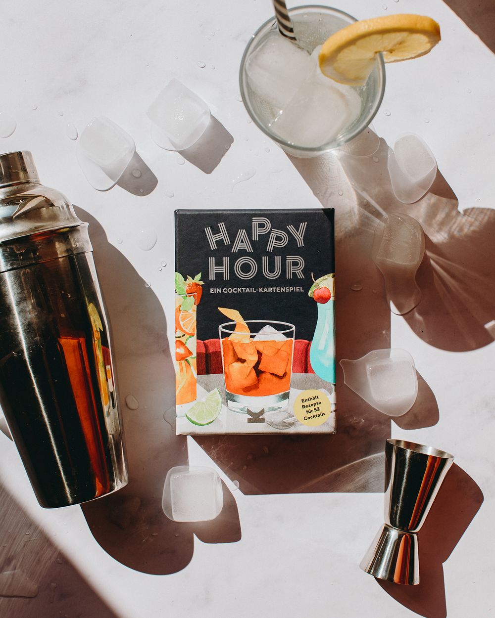 Cocktail recipe book titled 'Happy Hour' with a shaker and martini glass garnished with citrus in the background.