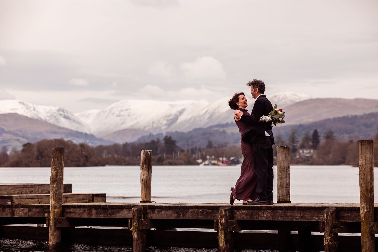 Bride and groom on the Storrs Hall lakeshore with snow on the hills behind them