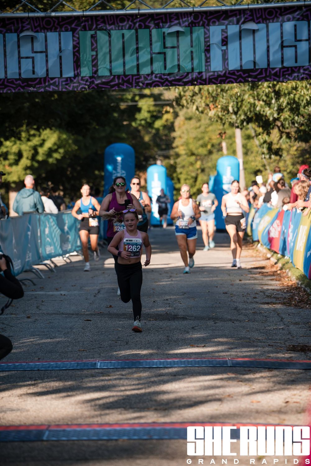 Runners compete on shaded path during outdoor racing event.