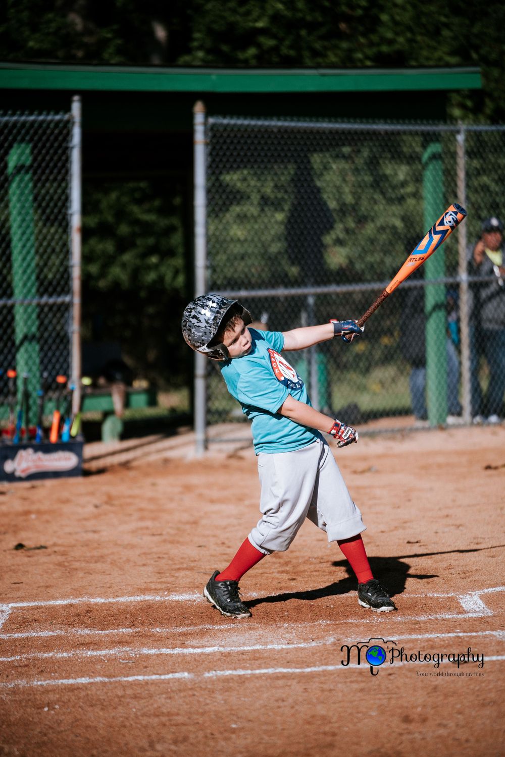 Baseball player in teal jersey makes dramatic sliding play on dirt infield.