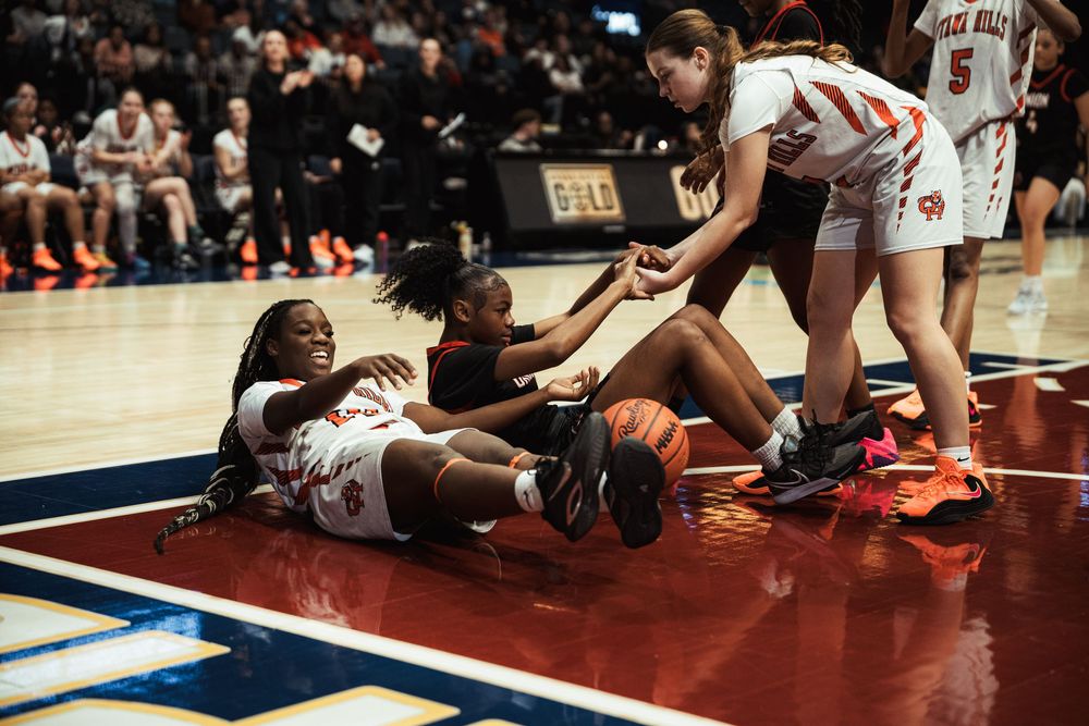 Multiple players scramble for possession of the basketball on the hardwood court.