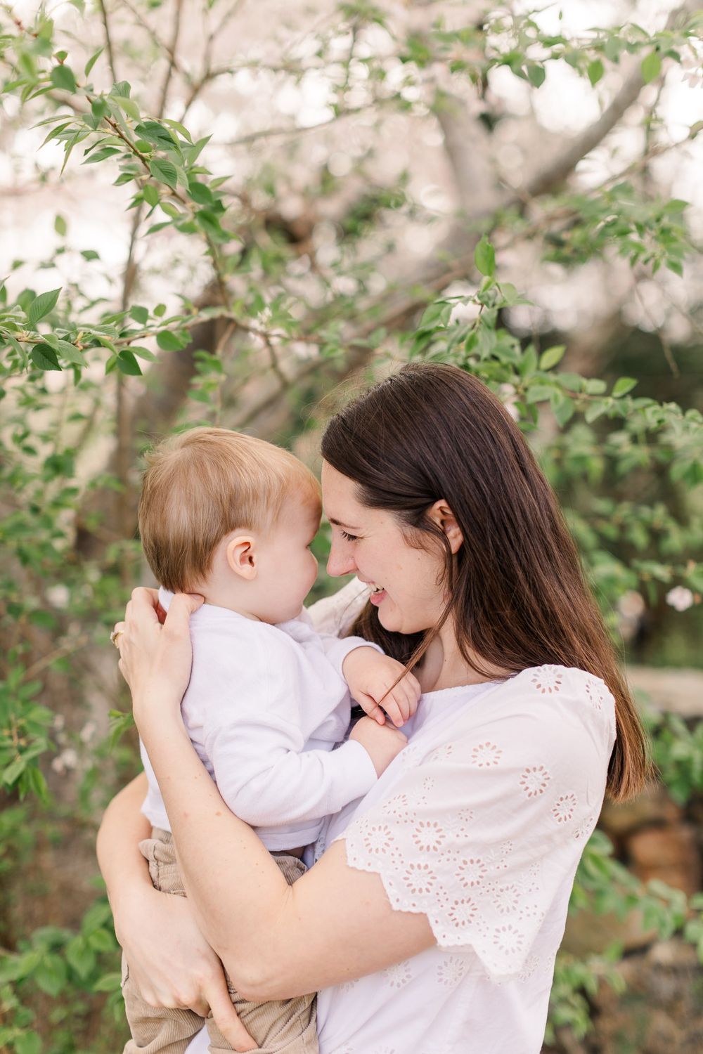 Spring family photo with mom holding baby son smiling among the spring blooms.