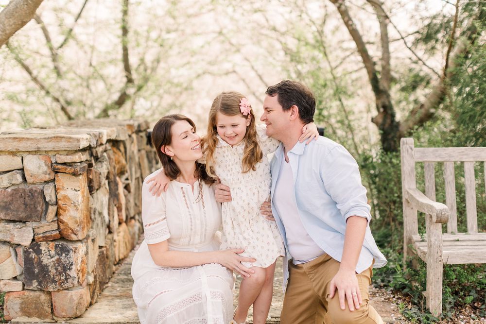 Mom and Dad with daughter smiling together among the Cherry blossoms in Richmond, Virginia.