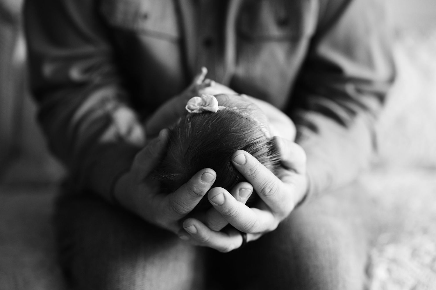 Black and white close-up photograph of hands gently holding a small baby's foot with delicate touch.