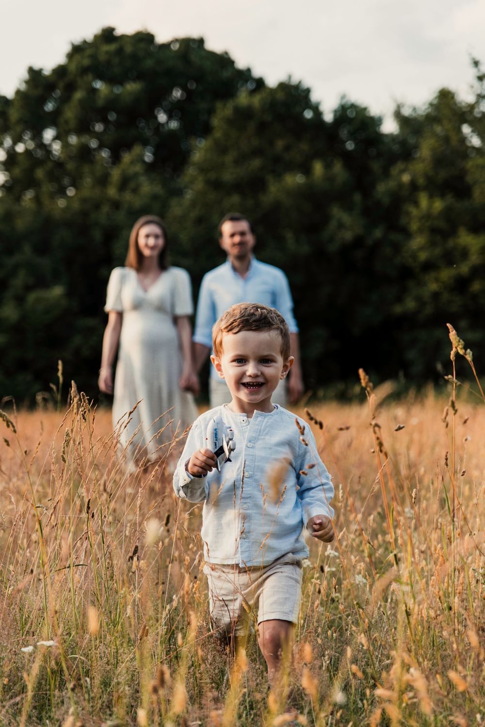 A joyful moment captured in a golden field with tall grass and trees in the background during sunset.