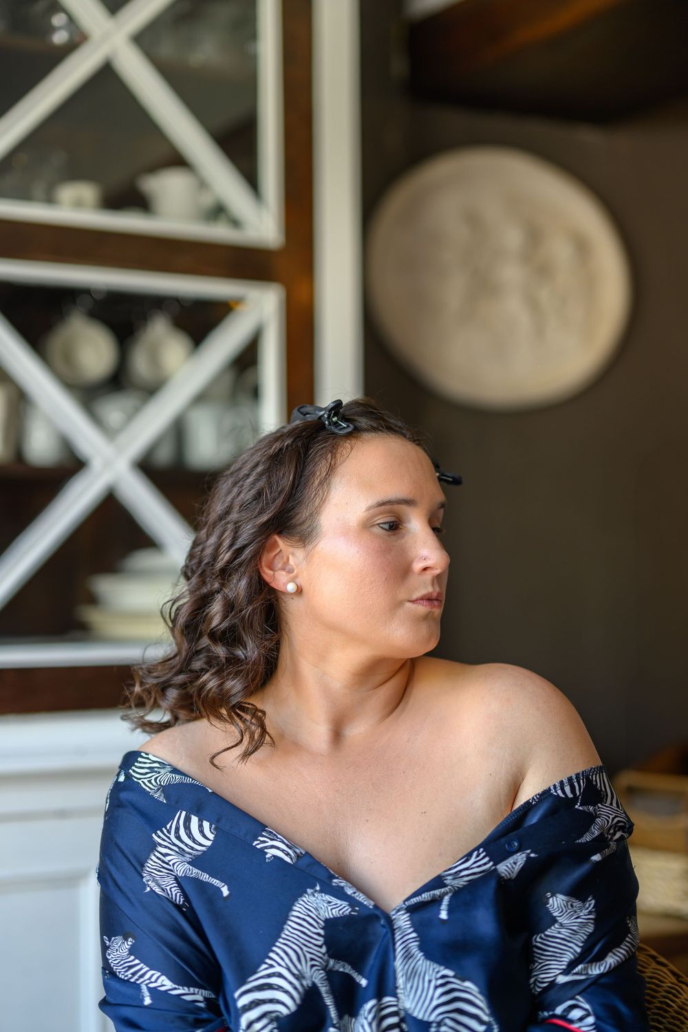 Woman in a navy blue floral dress sits gracefully while looking to the side.