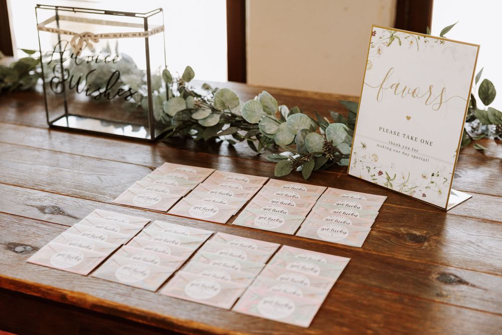 Wedding details cards and programs arranged on wooden table with eucalyptus garland decoration.