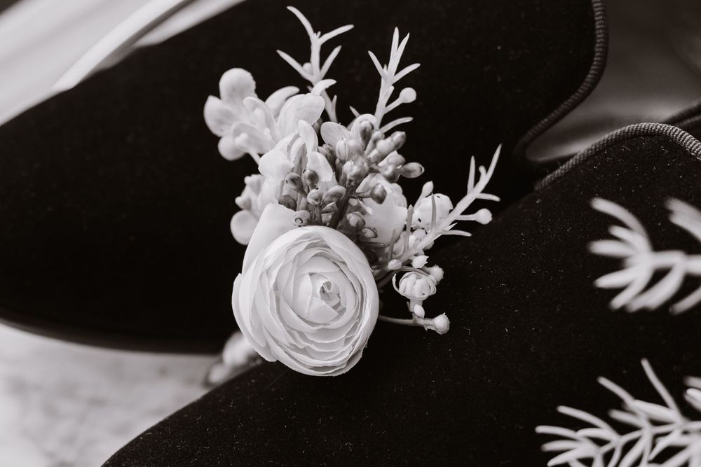 Black and white close-up photograph of delicate white floral boutonniere arrangement.