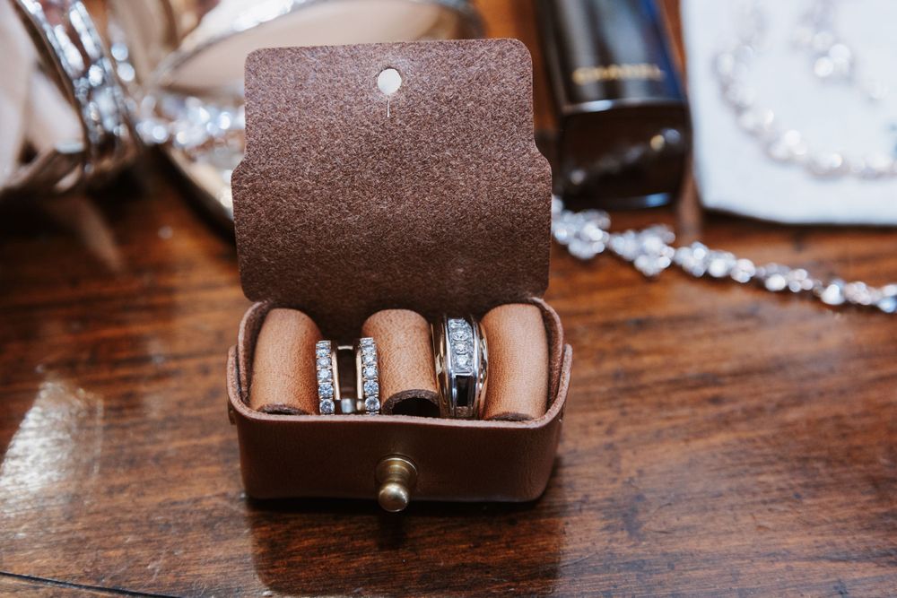 Three elegant wedding rings displayed in a brown leather ring box.