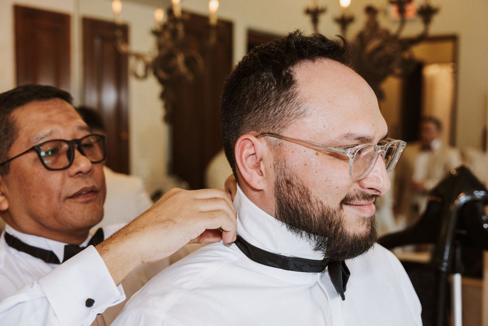 Getting ready scene with person having bowtie adjusted before ceremony.