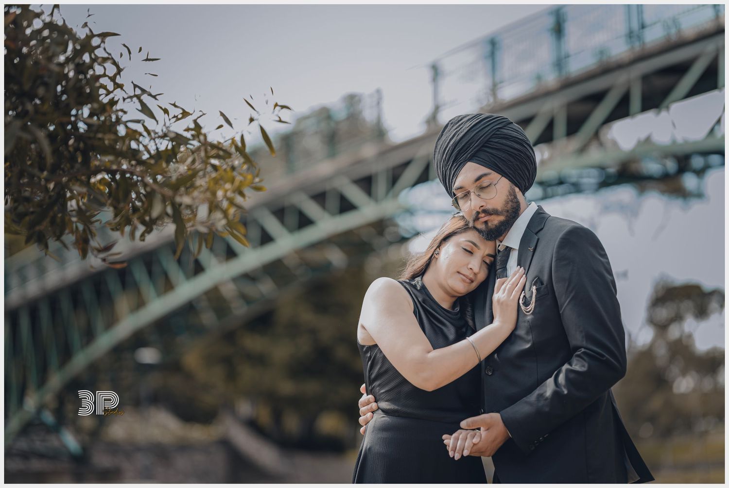 Romantic couple embraces under bridge during moody outdoor photoshoot.