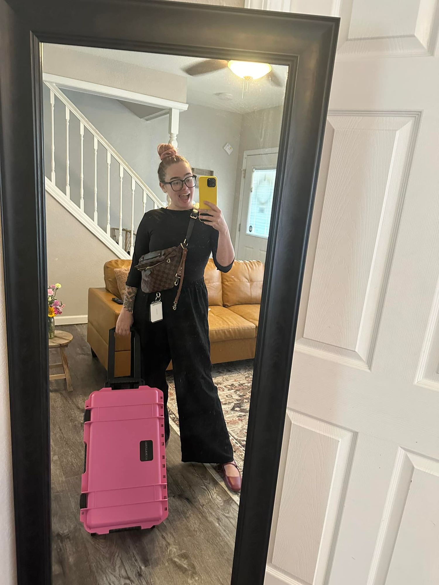 Person taking mirror selfies in a hallway with pink luggage.