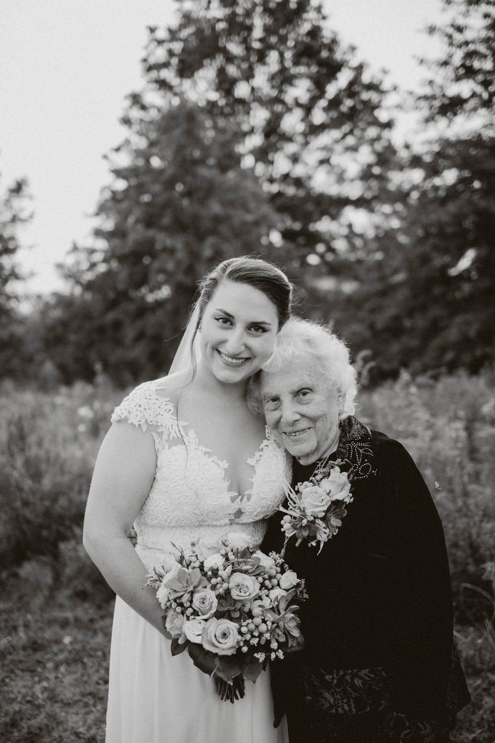 A black and white portrait showing a touching moment between people at a wedding, with elegant dress and bouquet details in frenchtown nj.