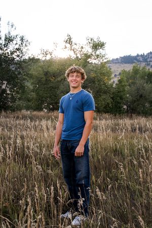 Person wearing blue shirt standing in a field of tall grass during golden hour.