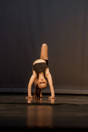 Modern dance performance sequence showing fluid movement and flexibility on dark stage.