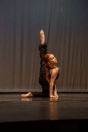 Contemporary dancer performs floor movements in a dramatic spotlight on stage.