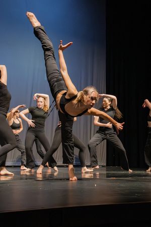Contemporary dance ensemble performs dynamic choreography with dramatic leg extensions on stage.