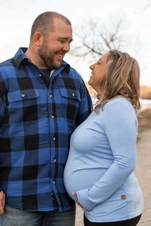 A couple in coordinating blue outfits share loving glances during an outdoor photo session.