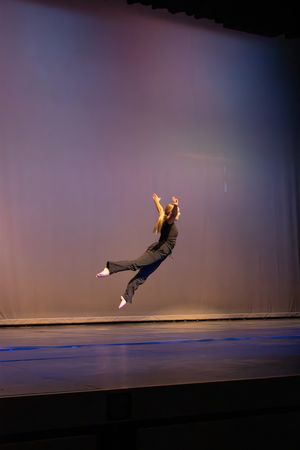 A sequence of dance movements showing a performer executing an athletic leap across a dark stage with dramatic lighting.