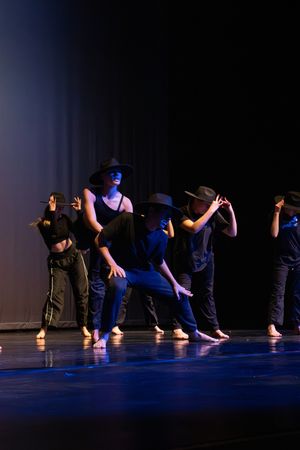 Modern dancers perform a synchronized floor sequence in dramatic blue stage lighting during a contemporary dance show.