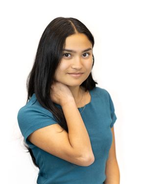 Young woman with long black hair wearing a teal t-shirt posing against a white background.
