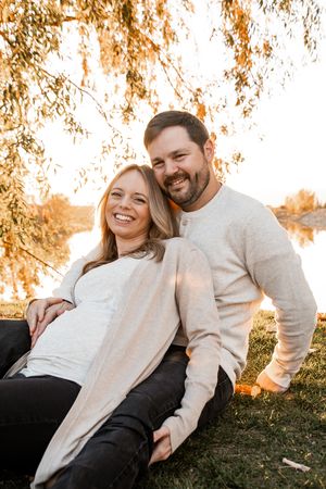 A couple shares joyful laughter while relaxing together outdoors during golden hour.