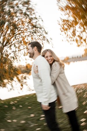 A couple spins joyfully together in a series of blurred motion shots against autumn foliage and water backdrop.