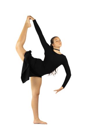 Young female dancer in black long-sleeve leotard performing a standing split, holding her leg overhead on white background.