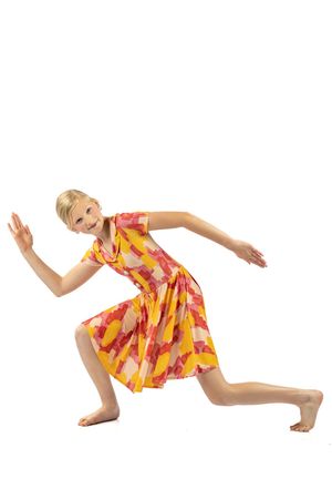 A blonde dancer in a colorful yellow and red dress performs a dynamic lunge pose against a white background.