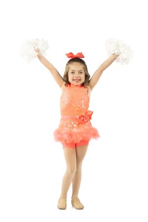 Young girl in orange sequin cheerleader costume holding white pom-poms with arms raised on white background.