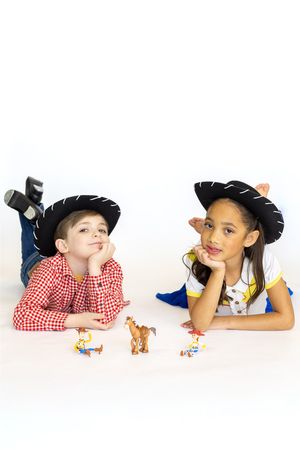 Creative portrait series of children wearing cowboy hats while playing with toy animals on white background.
