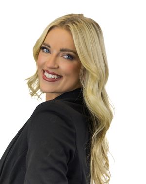 Woman wearing black blazer with blonde curled hair posing in a professional headshot series.