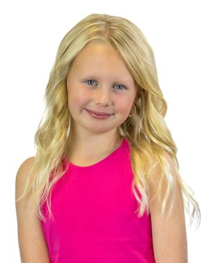 Little girl in bright pink sleeveless top with blonde wavy hair against white background.