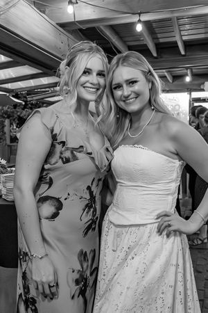 Two women in white dresses posing and smiling together at a formal event.
