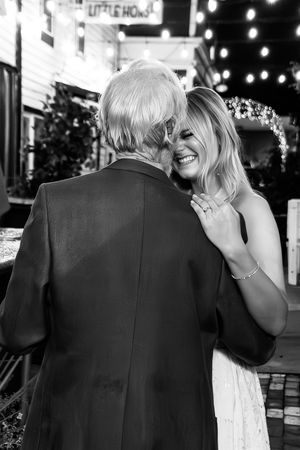 A candid black and white photo of a couple sharing a sweet moment together during a nighttime celebration.