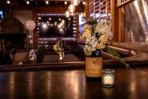 Elegant wedding venue with romantic string lights and floral centerpieces on dark wooden tables creating a warm atmosphere.