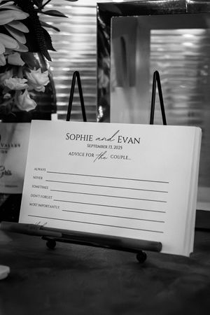 Black and white wedding guest book or sign-in sheets displayed on easels at a reception.