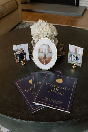University of Denver Sturm College of Law graduation programs displayed on a table with framed photos and white hydrangeas.